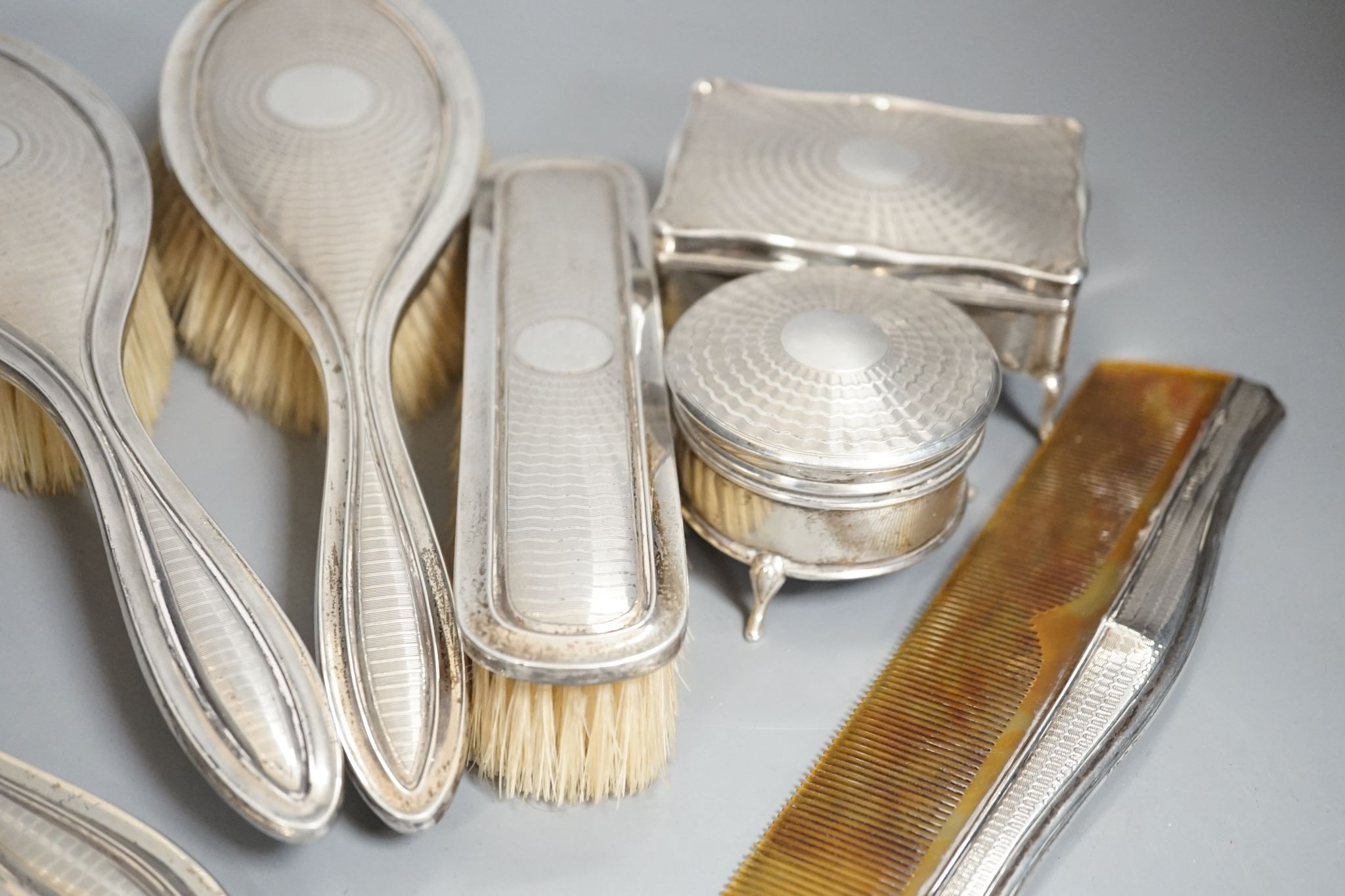 A George V engine turned silver seven piece dressing table set, comprising, two trinket boxes and a mirror, brush and comb set, Synyer & Beddoes, Birmingham, and Chester, 1912,13,14 and a silver mounted compact.